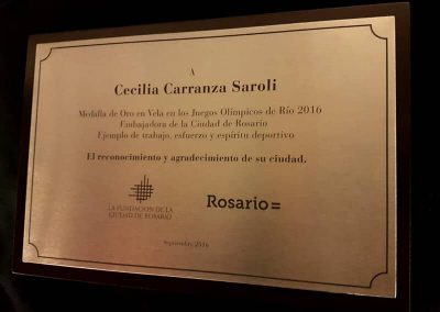 Placa de reconocimiento de acero inoxidable dedicada a Cecilia Carranza Saroli sobre base de madera