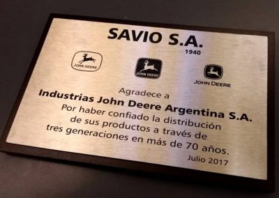 Plaqueta rectangular de acero inoxidable con logotipos de John Deere y texto de agradecimiento sobre base de madera