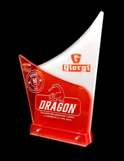 Reconocimiento con dos capas de acrílico. La de adelante tiene fondo rojo con texto y logotipo de la empresa Dragon y sello en blanco grabados con láser. La de atras tiene fondo blanco con el logotipo de la empresa Giorgi impreso digitalmente. Tiene dos capas mas de acrílico en la parte inferior a modo de base, sostenido todo con pernos de aluminio.